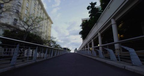 Ascending urban ramp toward horizon with metal railings and colonnade architecture perspective