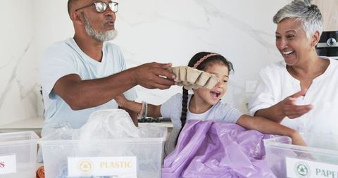 Grandfather and Granddaughter Recycling Together in Bright Kitchen