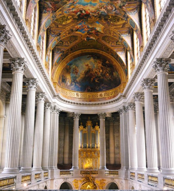 This image showcases the opulent interior of a grand cathedral, featuring elaborate Baroque architecture. The ceiling is adorned with intricate golden artwork and dramatic frescoes, while imposing columns create an awe-inspiring sight. Perfect for use in publications about historical architecture, religious studies, or cultural heritage, as well as for enhancing interior design inspiration.
