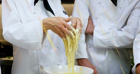 Chefs stretching sticky dough over mixing bowl during hands-on baking demonstration