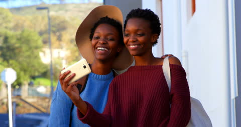 Joyful Twin Sisters Taking Selfie in Cityscape