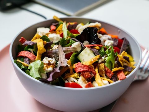 Colorful mixed greens salad featuring feta, cherry tomatoes and crispy tortilla strips