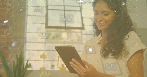 Professional woman using tablet in modern workspace with innovative icons