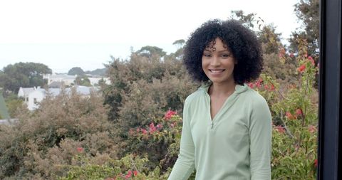 Woman Standing Outdoors Smiling Near Vibrant Flowers