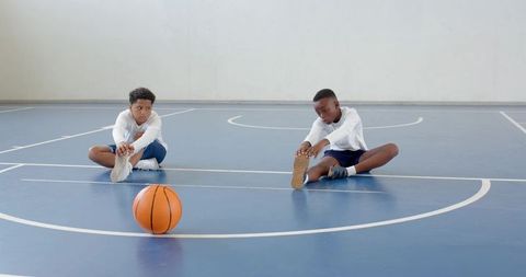 Boys Stretching on Basketball Court with Focus on Teamwork