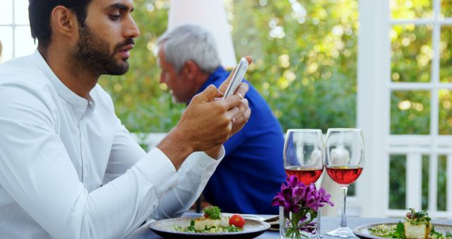 Young Man Using Smartphone at Outdoor Restaurant Table with Wine - Download Free Stock Images Pikwizard.com