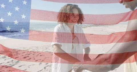 Friends holding sheer american flag on sunny beach celebrating summer freedom together