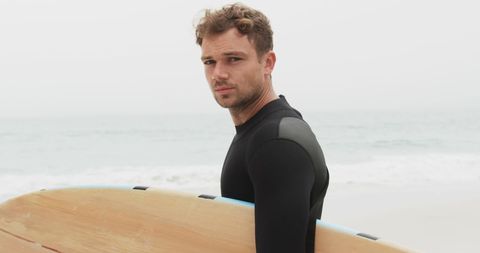 Confident Male Surfer with Board on Misty Beach