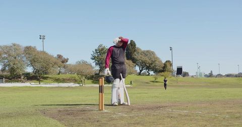 Cricketer Relaxing During Practice on Sunny Field Outdoors