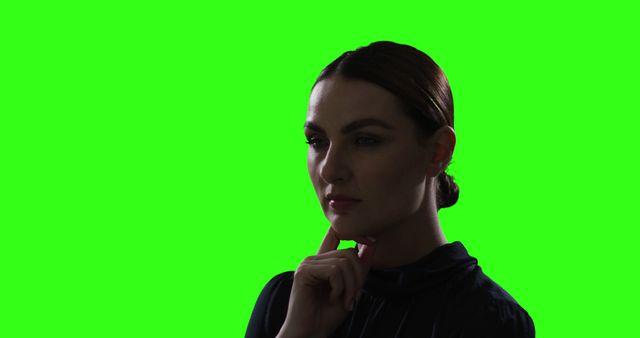 This image shows a businesswoman deep in thought with a green screen background. Perfect for presentations, advertisements, or enhancing with custom graphics and backgrounds to represent concepts of thinking, decision-making, professionalism, technical skills, or creative projects.