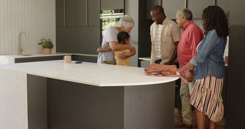 Multigenerational family embracing around marble kitchen island in contemporary home