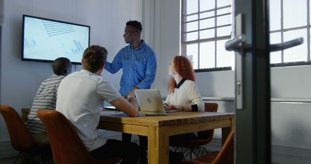 Young Team in Casual Meeting Analyzing Graphs on Large Screen - Download Free Stock Images Pikwizard.com