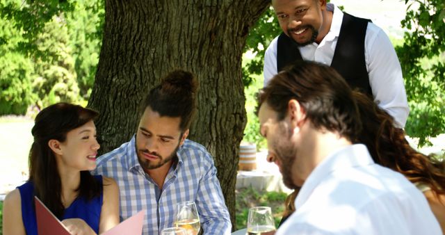 Diverse Group of Friends Dining Outdoors with Waiter - Download Free Stock Images Pikwizard.com