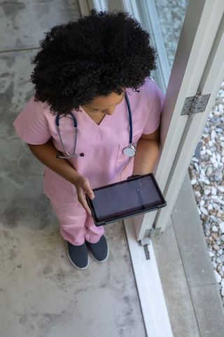 Nurse in pink scrubs using digital tablet in modern facility