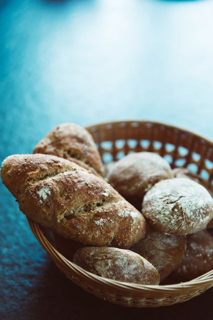 A basket filled with various types of artisan bread on a dark background, showcasing a rustic and healthy food choice. Perfect for bakery advertisements, organic food promotions, breakfast menu designs, and health-conscious food blogs.