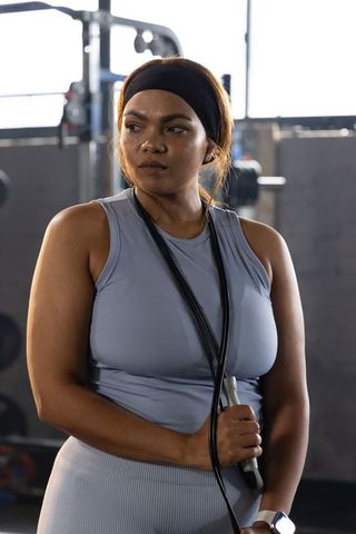 Fit african american woman holding jump rope wearing smartwatch showing strength and focus