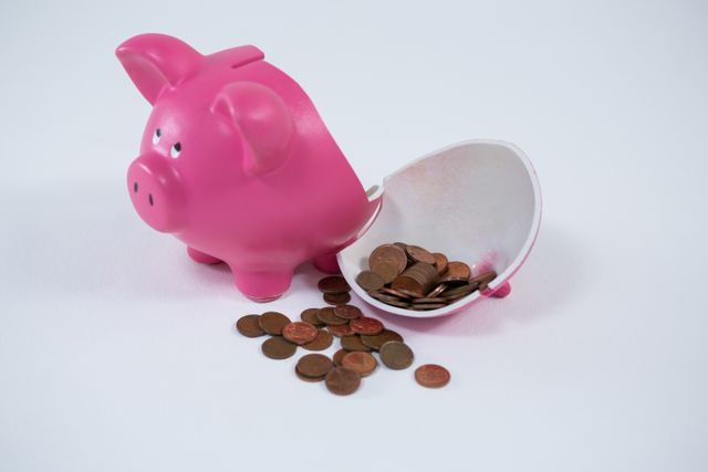 Pink piggy bank broken with money on white background