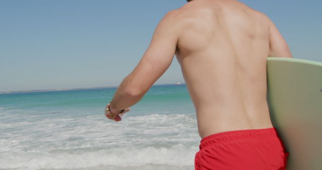 Young Caucasian man holding a surfboard at the beach - Download Free Stock Photos Pikwizard.com