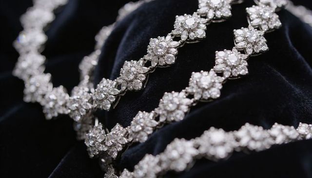 Sparkling floral cluster diamond necklace and bracelet lying on black velvet close-up
