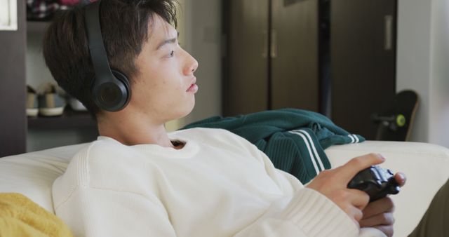 Young man playing video games with headphones at home - Download Free Stock Images Pikwizard.com