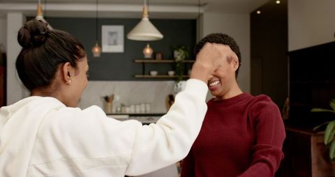 Playful phoric gesture between diverse friends in modern kitchen