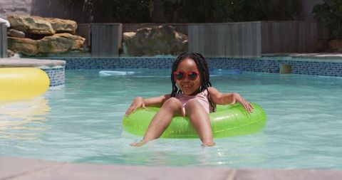 Joyful child relaxing in pool with inflatable and sunglasses