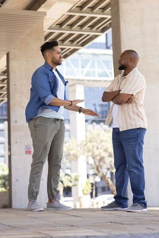 Two african american men having serious conversation under urban concrete overhang