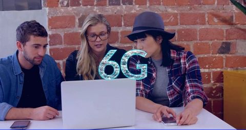 Team collaborating on 6g technology using laptop in urban brick-wall coworking studio