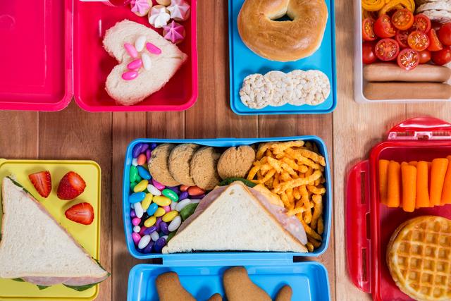Lunch box with various snack and sweet food on wooden table