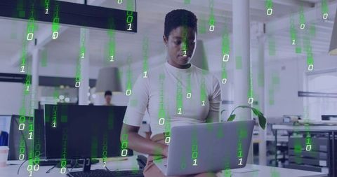 Professional woman working on laptop in modern open-plan office with digital code overlay