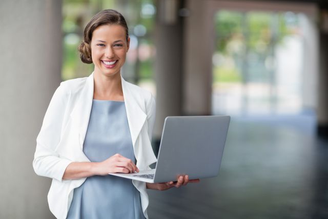 Portrait of a cheerful businesswoman holding laptop at conference centre