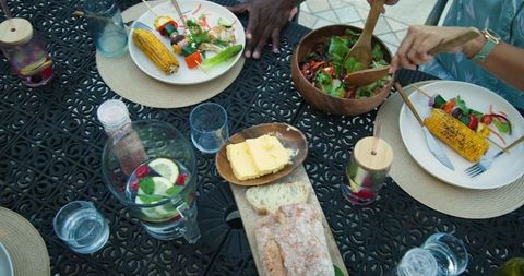 Friends enjoying outdoor dining with grilled vegetables and salad