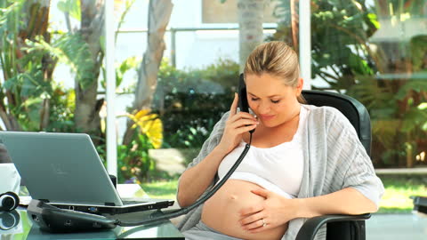 Expecting Professional Woman in Office Setting Communicating on Phone