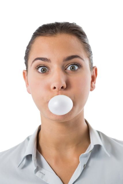 This image shows a young woman blowing a bubble with gum against a white background. It can be used in advertisements, blogs, or articles related to fun activities, leisure, youth culture, or lifestyle. It is also suitable for use in playful or humorous contexts.