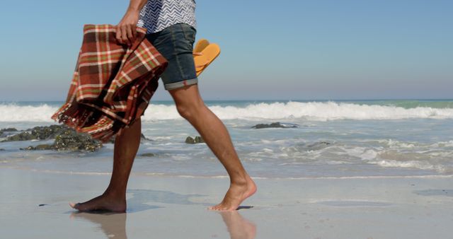 Man Walking Barefoot on Beach Carrying Blanket and Flip Flops - Download Free Stock Images Pikwizard.com