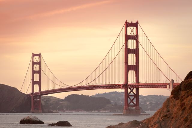 Golden Gate Bridge bathed in the warm hues of sunrise over the San Francisco Bay Area shows its architectural beauty and iconic status. Perfect for travel websites, tourism brochures, and promotional material conveying the charm of San Francisco, California, and American landmarks.