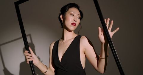 Elegant woman in black dress holding frame, studio fashion portrait