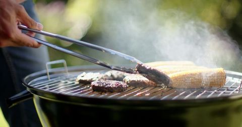 Cooking burgers and corn on a backyard charcoal grill