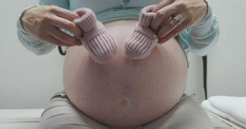 Expectant mother holding baby booties on pregnant belly