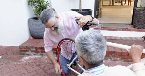 Senior Couple Repairing Bicycle on Brick Patio