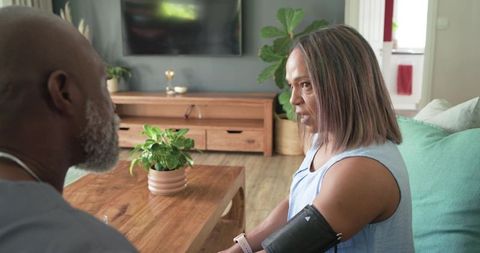 Couple checking blood pressure at home with wearable cuff in modern living room
