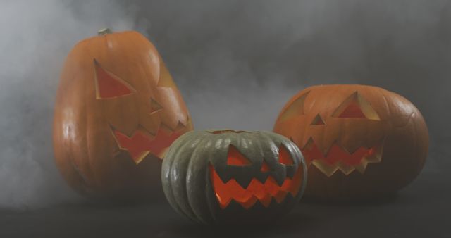 Smoke effect over multiple scary face carved halloween pumpkin against grey background. halloween holiday and celebration concept