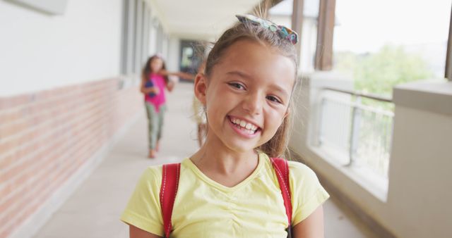 Smiling Young Girl in School Corridor with Friend in Background - Download Free Stock Images Pikwizard.com