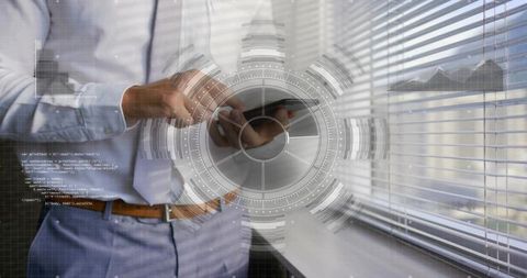 Businessman standing tapping smartphone by office window with hud overlay, code graphics