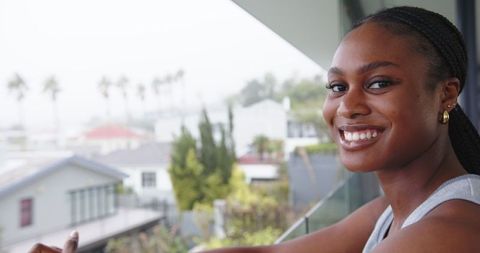 Content Woman on Balcony with Urban Backdrop