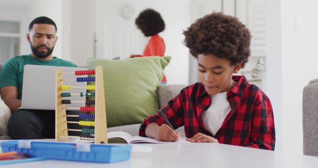 Focused Child Studying at Home with Family in Background - Download Free Stock Images Pikwizard.com