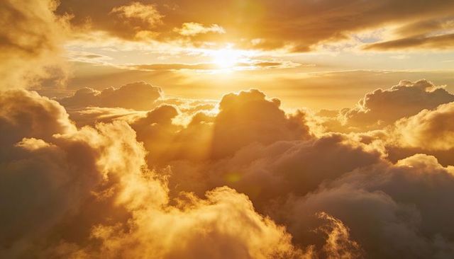Bathing cumulus clouds in golden sunset light with radiant sun rays and glowing horizon
