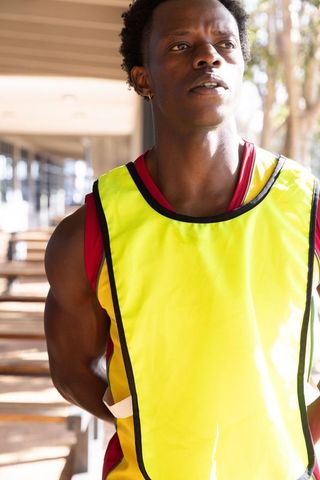 Determined Athlete in Yellow Vest Training Outdoors by Benches