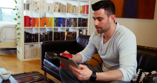 Man Relaxing on Sofa Reading Tablet, Red Mug in Hand - Download Free Stock Images Pikwizard.com