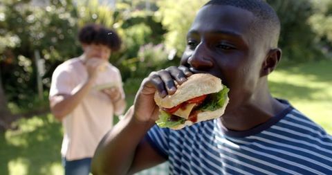 Friends Enjoying Hamburgers in Sunny Outdoor Yard Gathering
